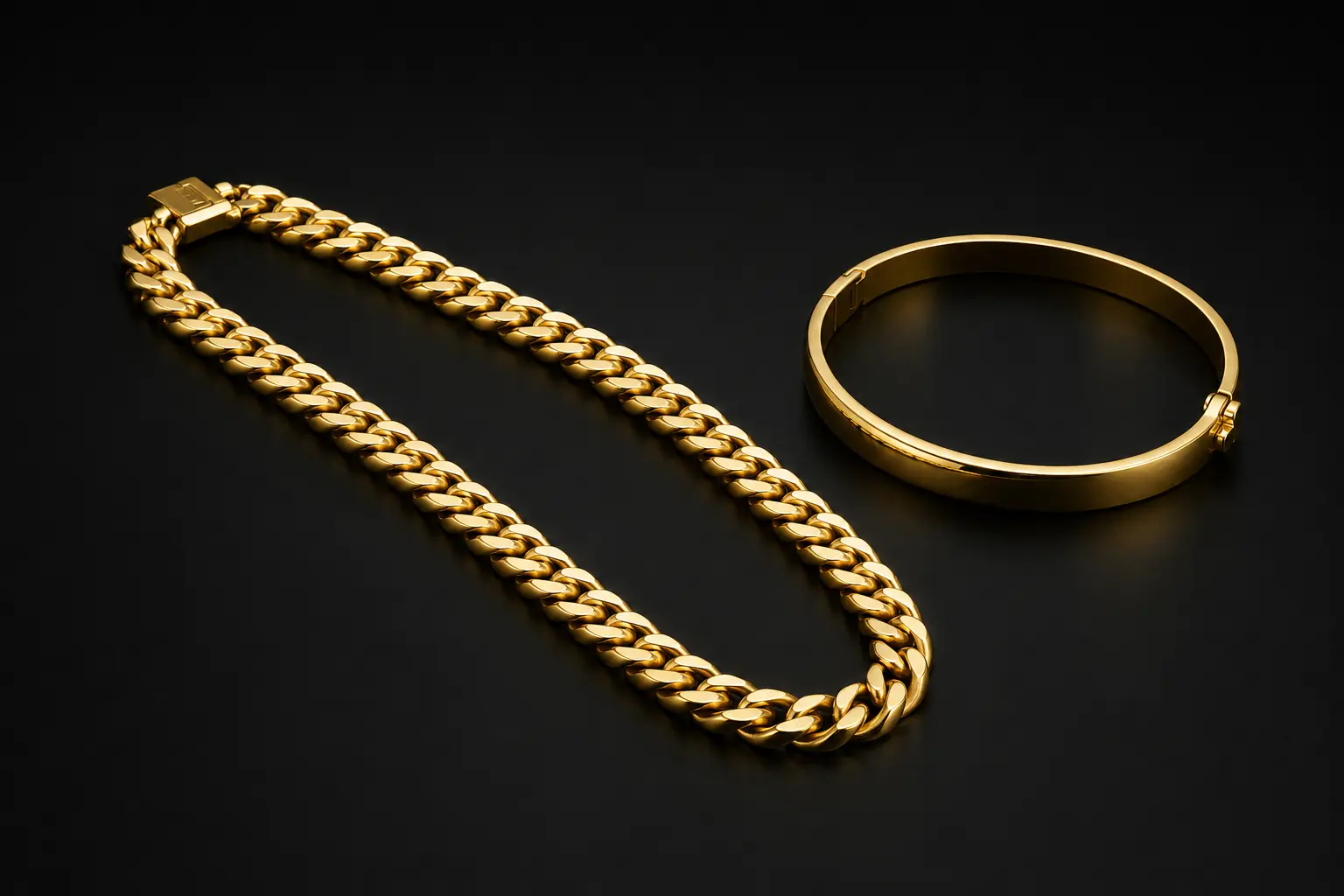 Classic polished gold curb chain and hinged bangle on a charcoal background