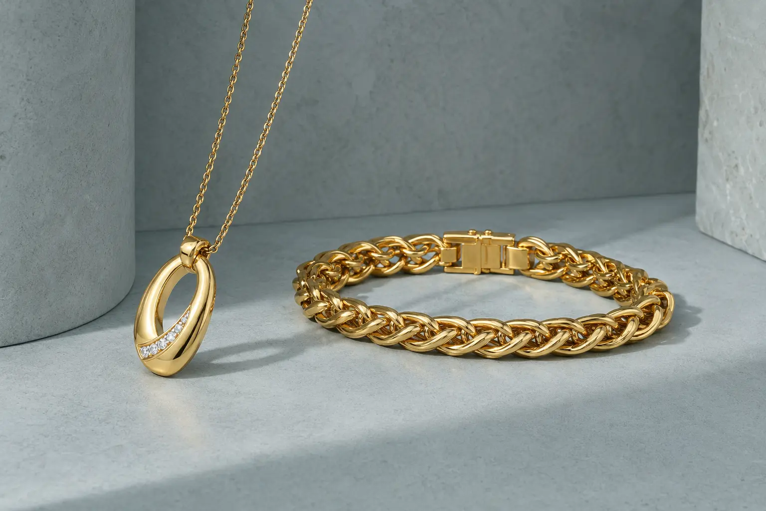 Gold pendant and substantial bracelet on a cool celadon architectural surface